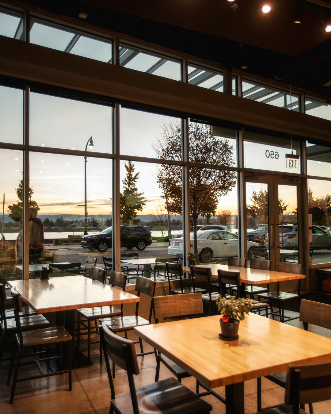 our-story a-restaurant-with-large-windows-and-wooden-tables-xcy9lyifffo